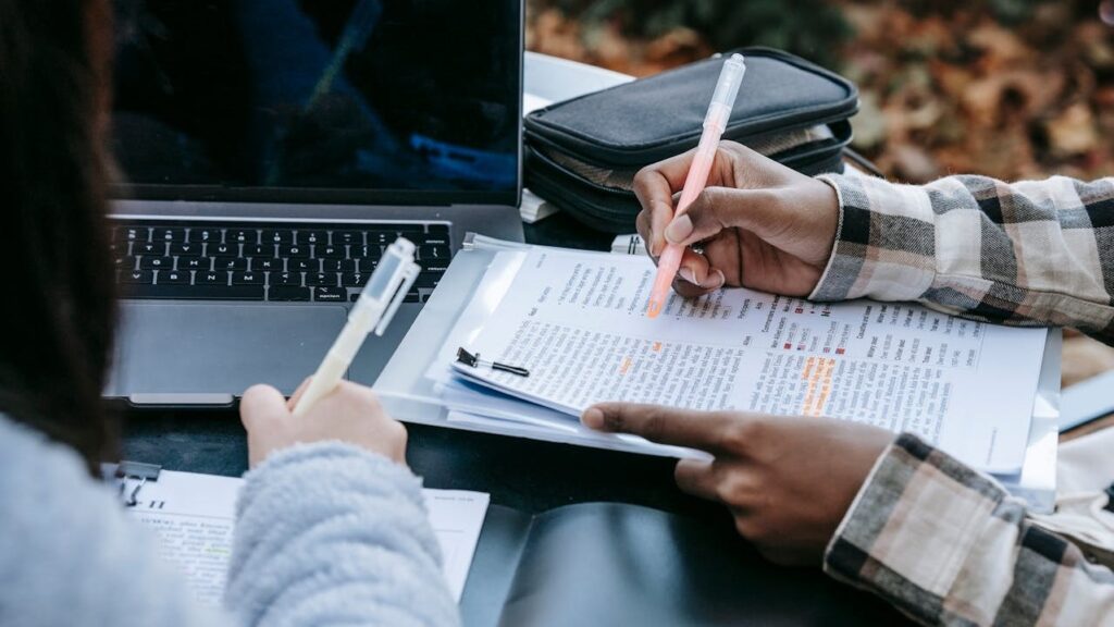 Twee mensen bespreken financiële documenten met laptop erbij, passend bij administratiekantoor kiezen.