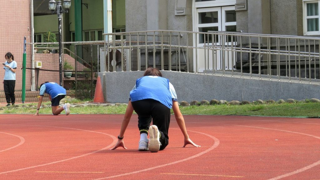 Atleet in startpositie op atletiekbaan toont voorbereiding en focus op balans en snelheid
